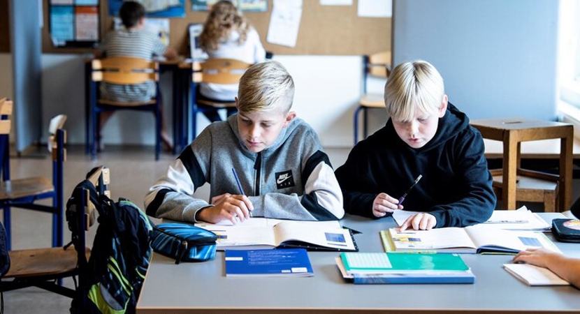 To elever sidder ved et bord i klasselokalet