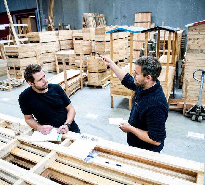 To personer taler sammen i en produktionshal