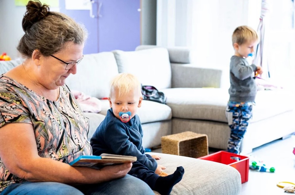 Dagplejemor læser højt fra bog mens 2 årig lytter