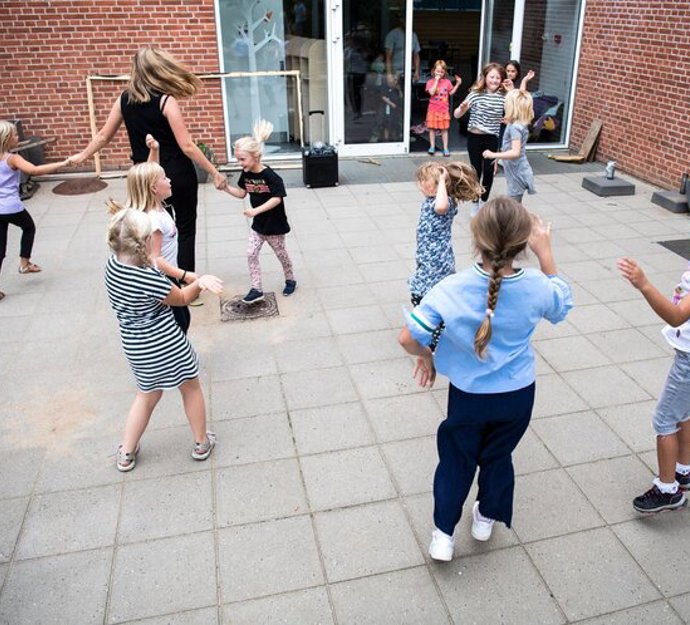 En gruppe børn danser og har det sjovt i skolegården